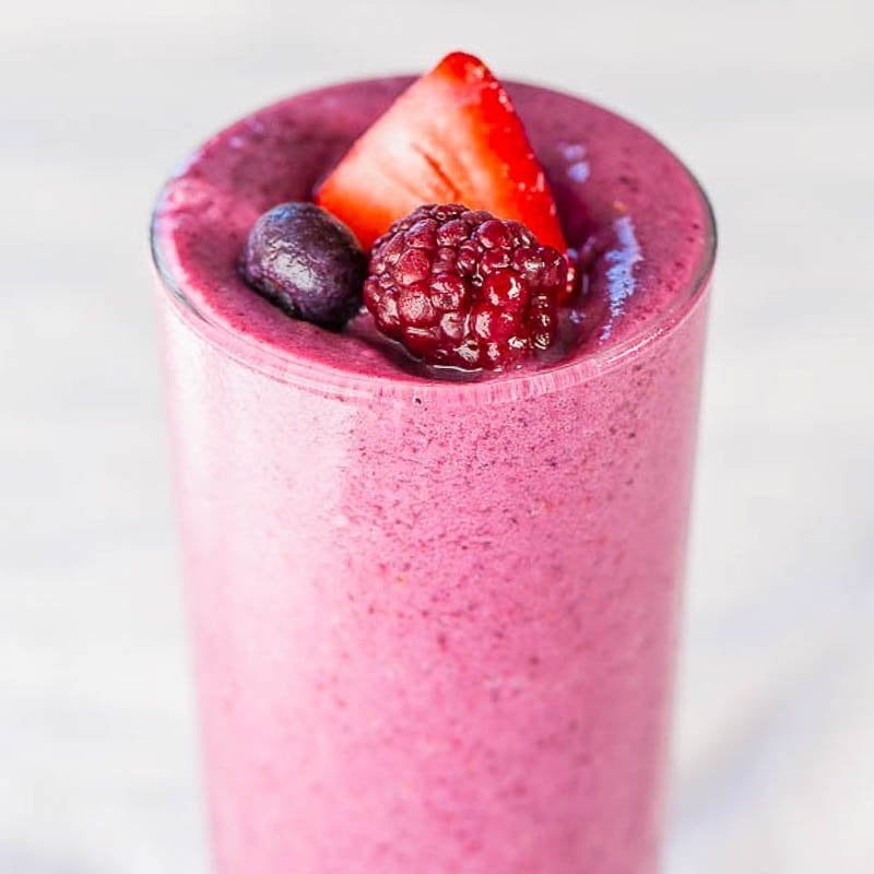 Berry smoothie topped with fresh strawberries, blueberries, and a raspberry.