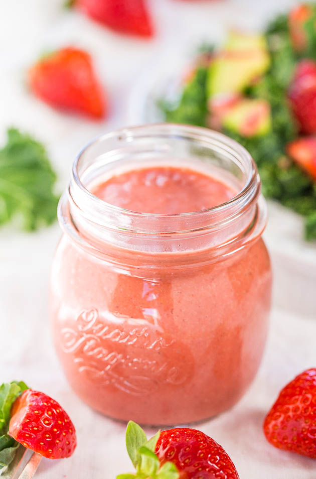 strawberry dressing in a glass jar with fresh berries in the foreground 