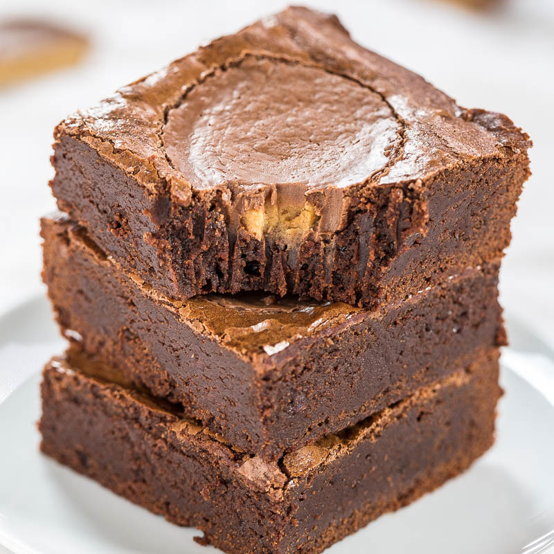 Three stacked chocolate brownies with a glossy crust on a white plate.