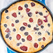 Freshly baked berry clafoutis in a cast-iron skillet, dusted with powdered sugar.