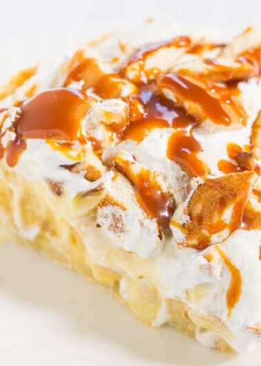 A slice of apple pie topped with whipped cream and caramel sauce.