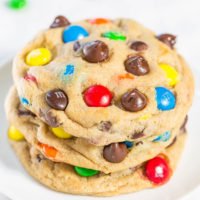 A stack of chocolate chip cookies with colorful candy pieces on a white background.