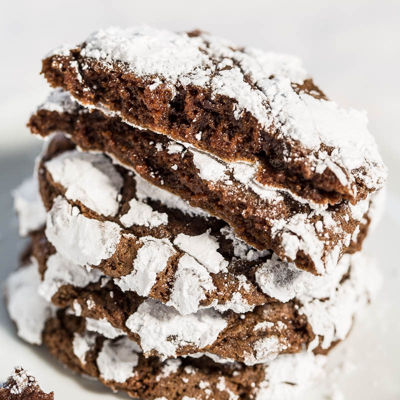 Stack of chocolate crinkle cookies with powdered sugar on top.