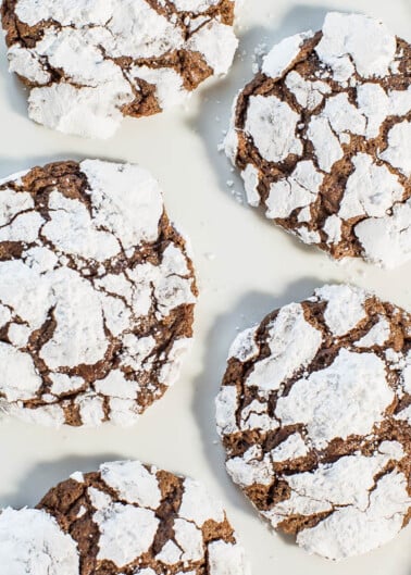 Plate of cracked chocolate cookies dusted with powdered sugar.
