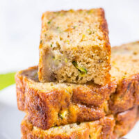 Sliced zucchini bread stacked on a plate.