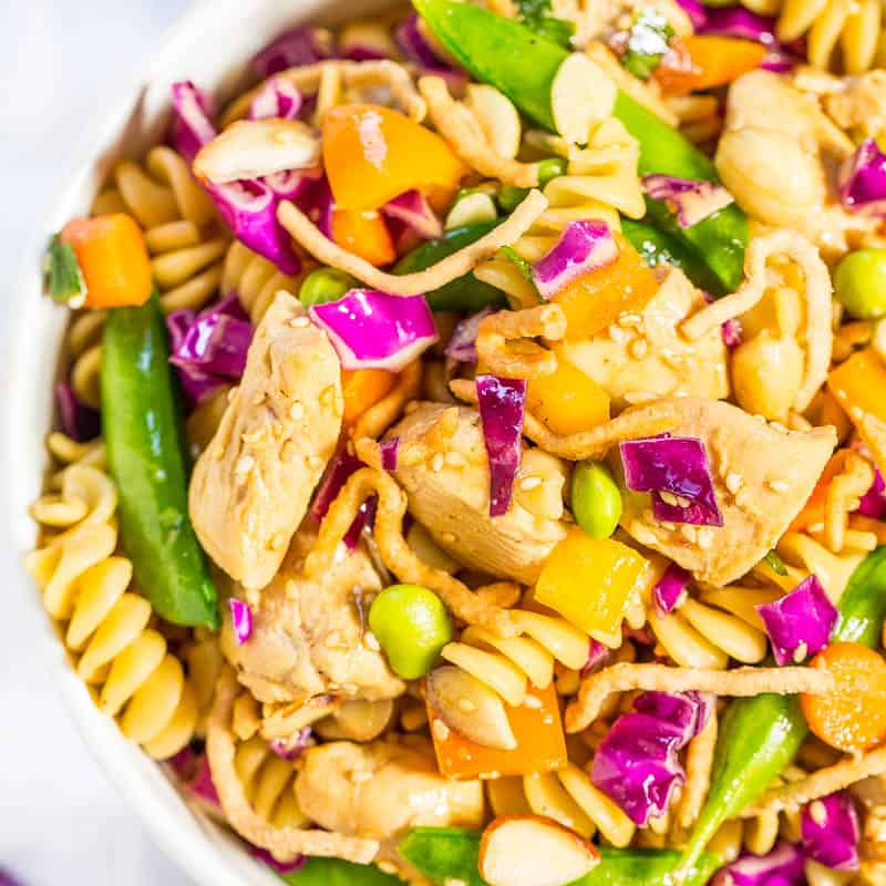 A colorful asian chicken pasta salad with vegetables and sesame seeds in a bowl.