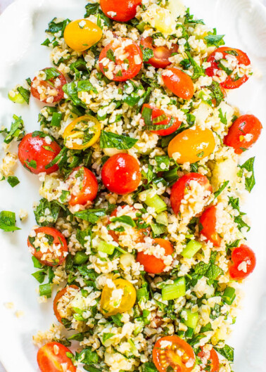 A plate of tabbouleh salad with cherry tomatoes, chopped parsley, and bulgur wheat.