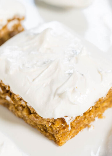 A slice of carrot cake with cream cheese frosting on a white plate.