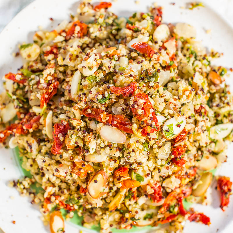 A plate of quinoa salad mixed with sliced almonds, herbs, and sun-dried tomatoes.