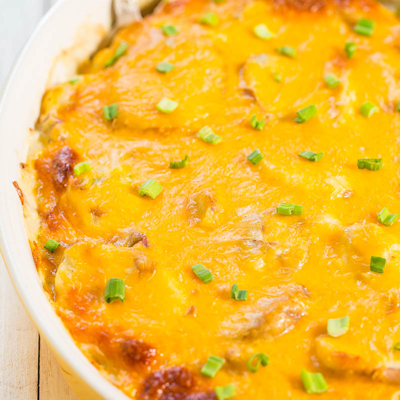 A baked casserole topped with melted cheddar cheese and garnished with chopped green onions.