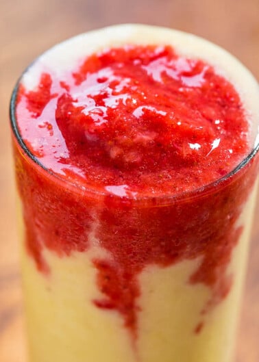 A layered smoothie with a bright yellow base topped with a vibrant red puree.