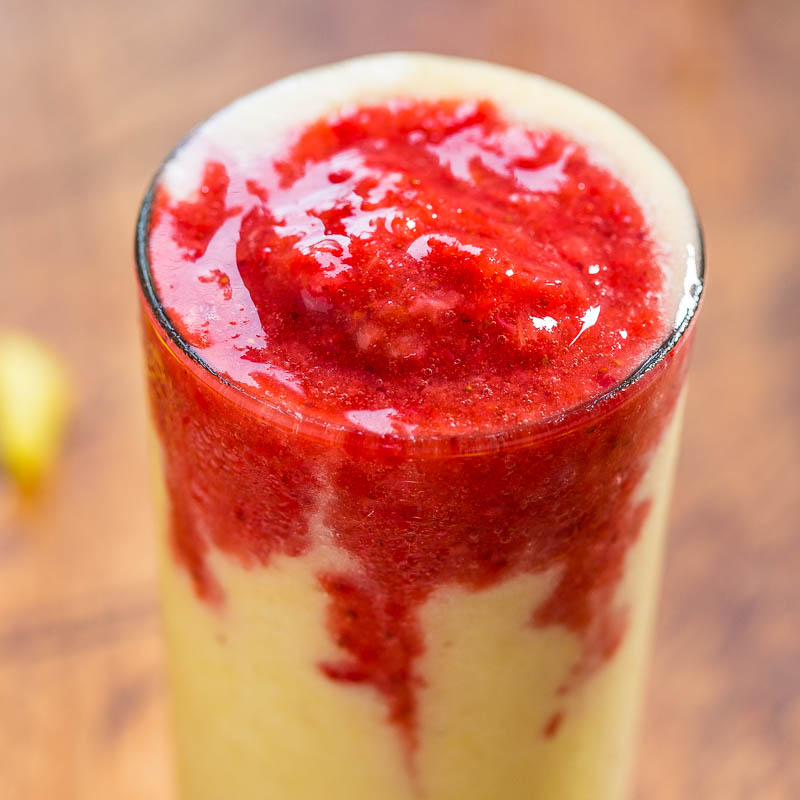 A layered smoothie with a bright yellow base topped with a vibrant red puree.