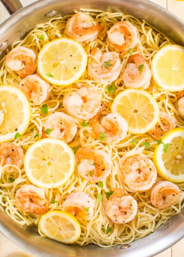 A bowl of shrimp pasta garnished with lemon slices and herbs.