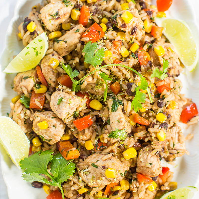 Colorful chicken and rice dish garnished with lime wedges and cilantro.