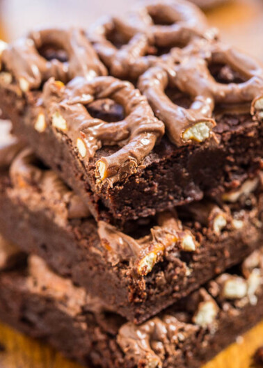 A stack of chocolate brownies with nuts and drizzled chocolate on top.
