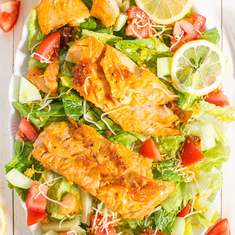 Grilled salmon fillets on a fresh garden salad with lemon slices.