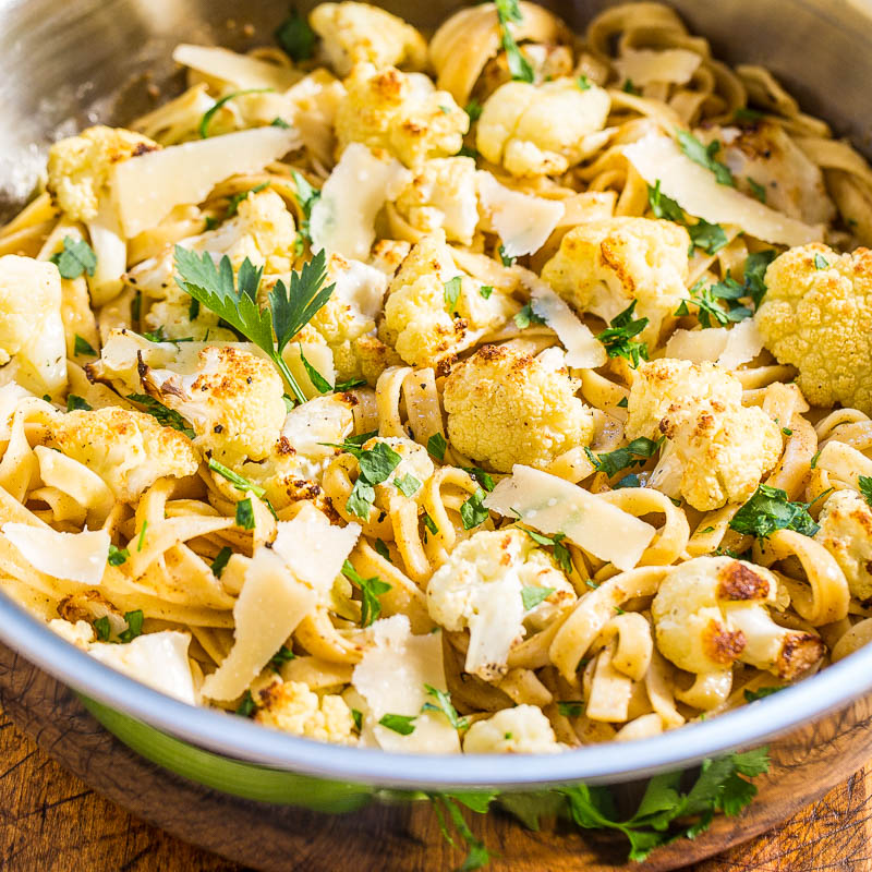 A bowl of pasta with roasted cauliflower and shaved cheese, garnished with parsley.