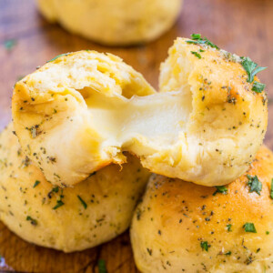 Freshly baked cheese-stuffed garlic bread rolls on a wooden surface.