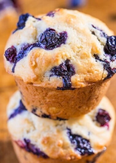 Blueberry muffin stacked on top of another, showcasing its baked berries and golden-brown crust.