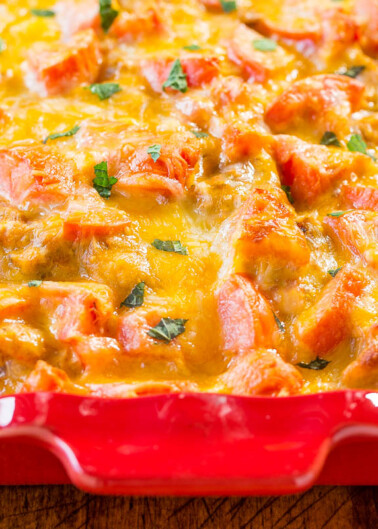 Baked cheesy casserole with tomato and herbs in a red dish.
