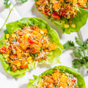 Fresh taco salad cups with grilled chicken, vegetables, cheese, and corn served on a white plate.