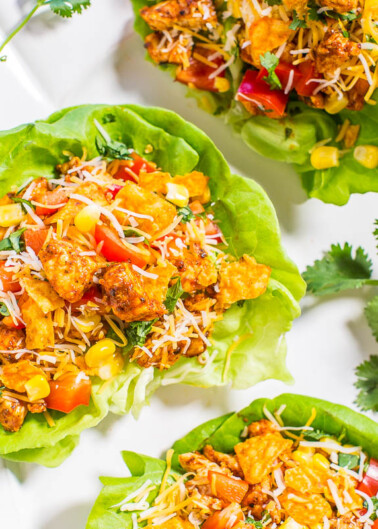 Fresh taco salad cups with grilled chicken, vegetables, cheese, and corn served on a white plate.