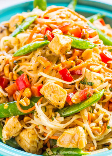A plate of stir-fried noodles with chicken, snap peas, and red bell peppers.