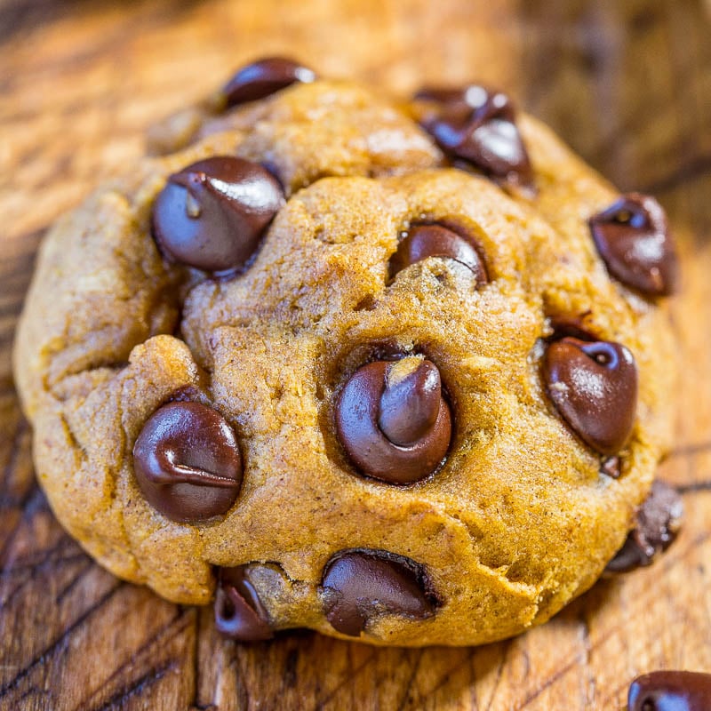 A close-up image of a chocolate chip cookie on a wooden surface.