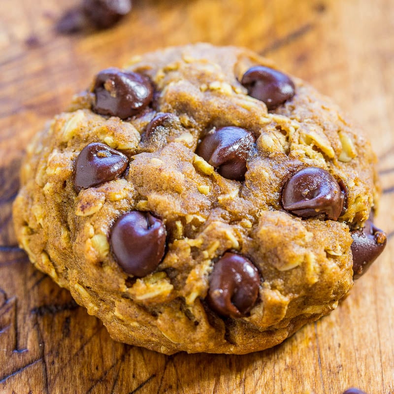 A close-up shot of a chocolate chip cookie on a wooden surface.
