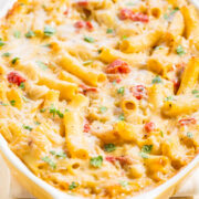 Baked cheesy pasta with tomato pieces and garnished with parsley in a baking dish.