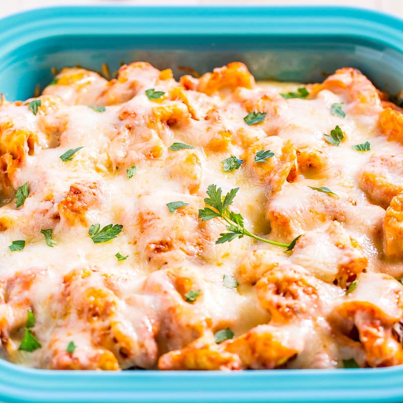 A baking dish filled with baked pasta topped with melted cheese and garnished with parsley.