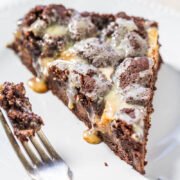 A slice of chocolate cookie pie with a melting scoop of ice cream on top, partially eaten with a fork on the side.