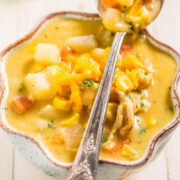 Bowl of chunky vegetable soup with a spoon.