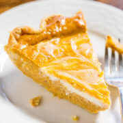 A slice of peach pie on a white plate with a fork.