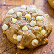A close-up of a cookie with white chocolate chips and sprinkled sugar on a wooden surface.