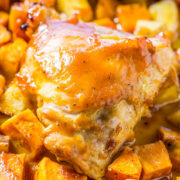 Roasted chicken thigh atop seasoned vegetables with a golden-brown glaze.