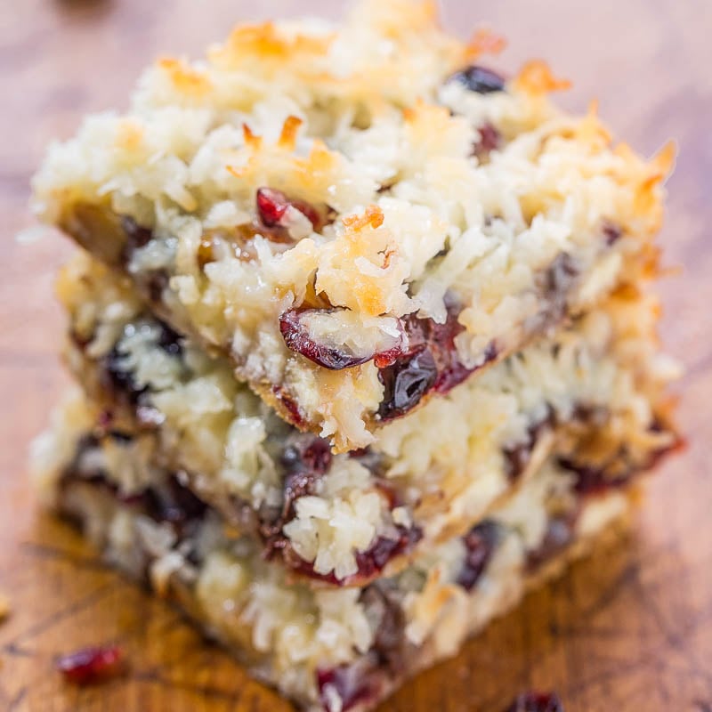 A stack of coconut cranberry bars on a wooden surface.