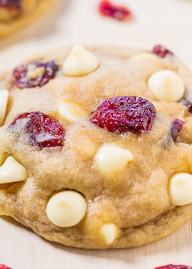 White chocolate chip and cranberry cookie on a wooden surface.