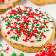 A sugar cookie with white frosting and red and green sprinkles.