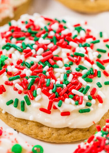 A sugar cookie with white frosting and red and green sprinkles.