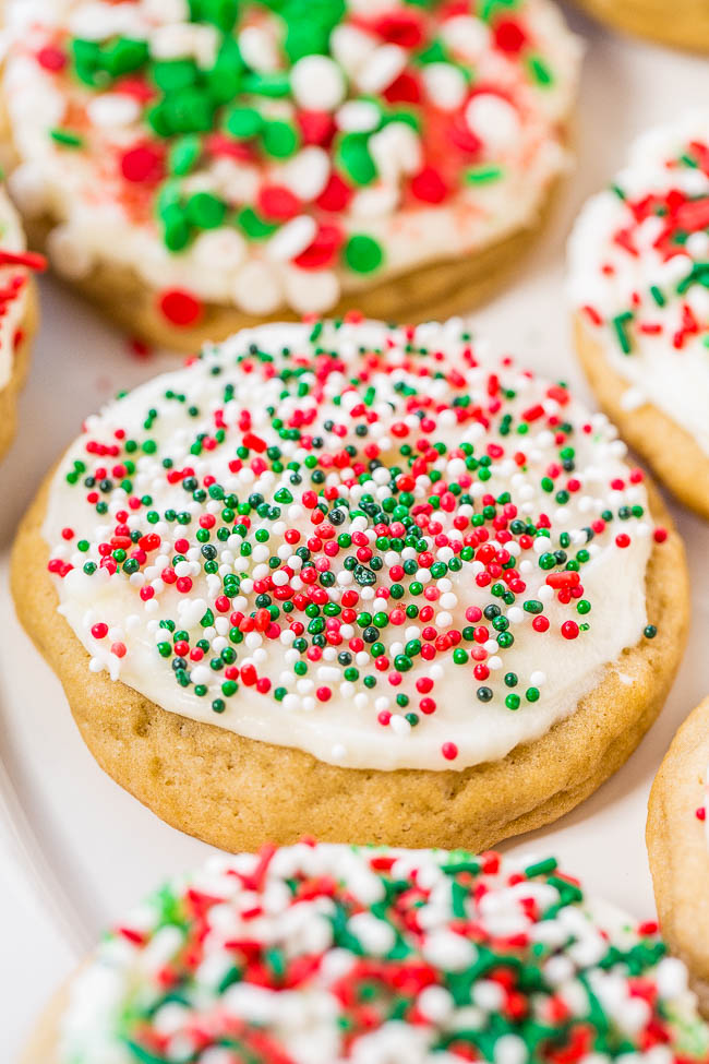 close up of a holiday sugar cookie topped with cream cheese frosting and holiday sprinkles. 