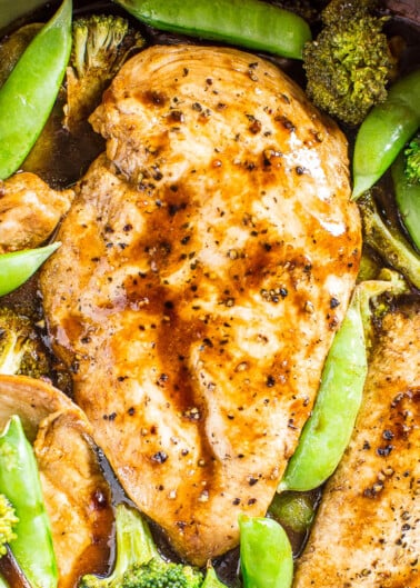 Grilled chicken breasts with broccoli and snap peas in a savory sauce.