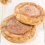 Two cinnamon sugar-coated cookies on a wooden surface.