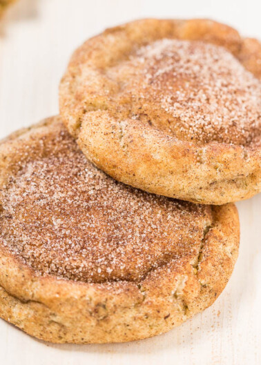 Two cinnamon sugar-coated cookies on a wooden surface.