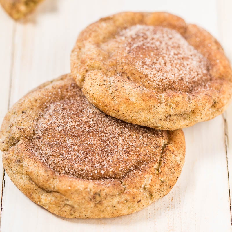 Two cinnamon sugar-coated cookies on a wooden surface.