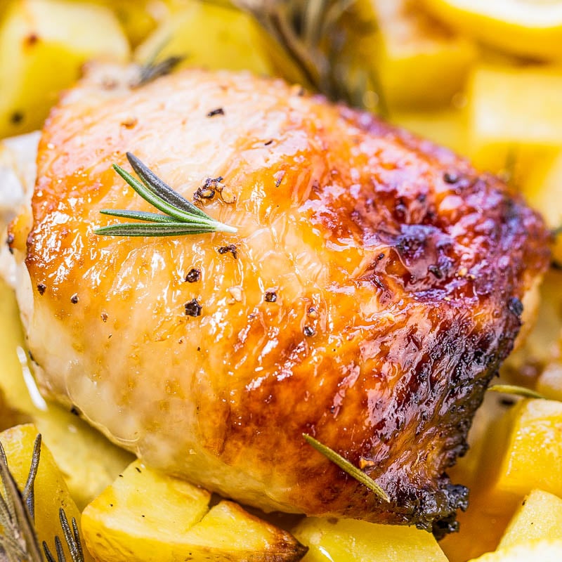 Roasted chicken thigh with herbs on a bed of diced potatoes.