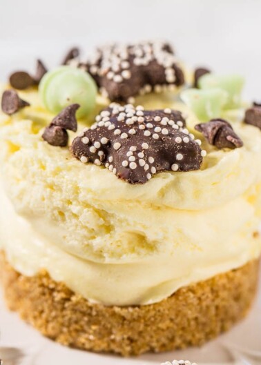 A close-up of a creamy layered dessert garnished with chocolate chips and decorative chocolate pieces.