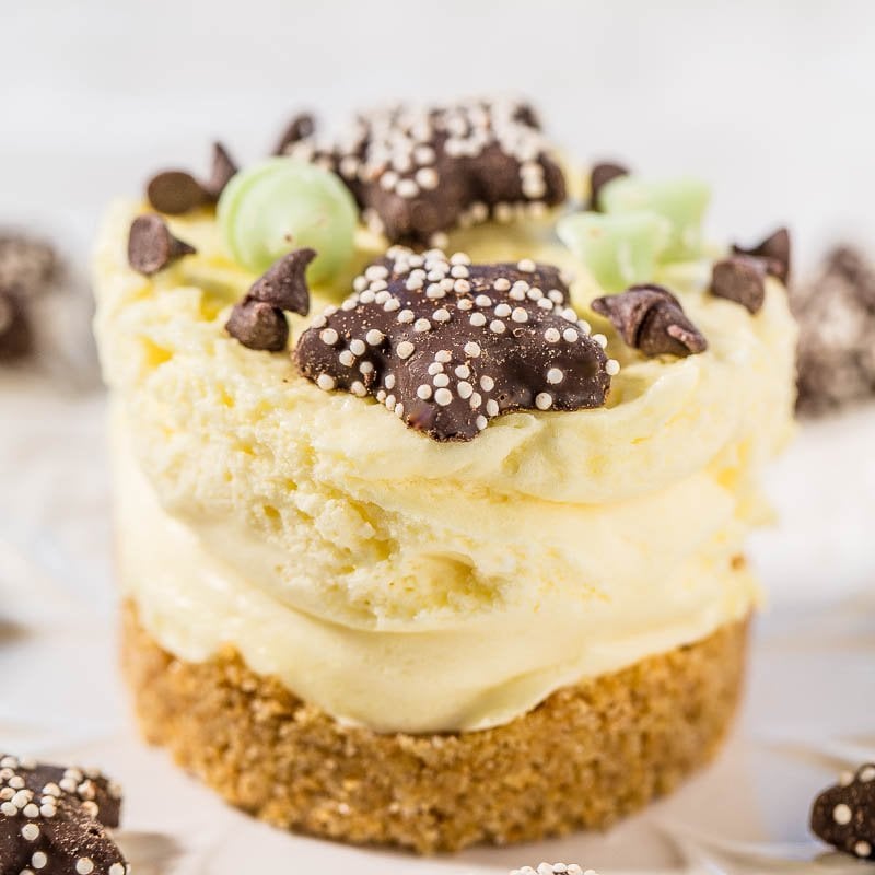 A close-up of a creamy layered dessert garnished with chocolate chips and decorative chocolate pieces.