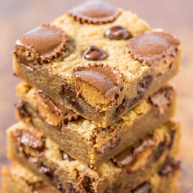 A stack of chocolate chip cookie bars with peanut butter cups on a wooden surface.