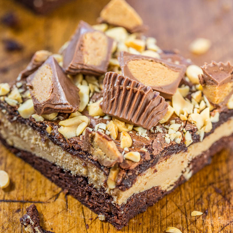 A close-up of a chocolate brownie topped with peanut butter cups and chopped nuts.